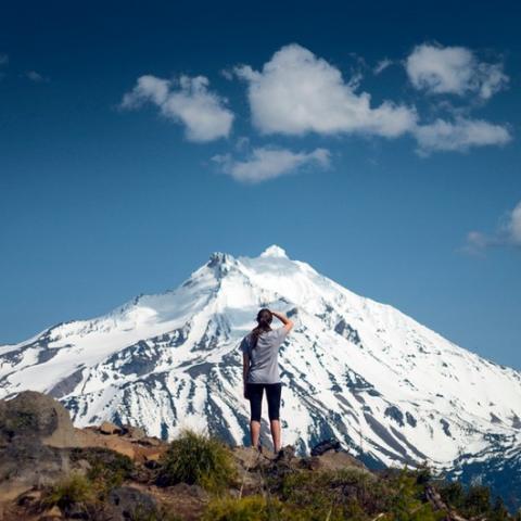 Woman standing looking at snow covered mountain in the distance