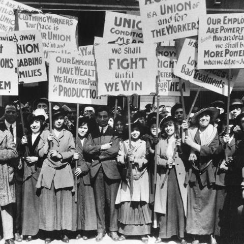 image from Progressive Era of large group of women and men holding signs with worker's rights slogans