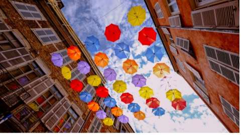 Colorful umbrellas suspended from sky between two buildings