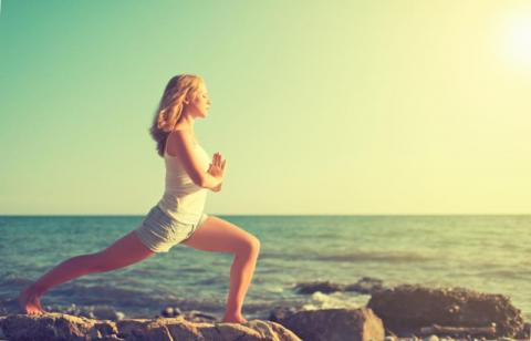 woman doing yoga on rocky beach