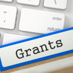 Labeled file folder "grants" resting on a computer keyboard