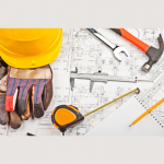 building tools on drafting table - measuring tape, hammer, hardhat, gloves, wrench, pencil