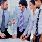 group of employees around their boss listening and reviewing documents