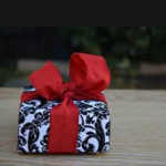 image of wrapped gift with big red bow sitting on porch deck