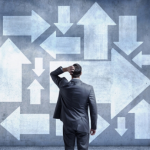 man in suit scratching his head looking at wall of white arrows all pointing in different directions