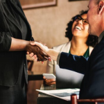 image of man shaking woman's hand as she approached the table where he is sitting