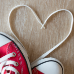 photo of shoe strings formed in the shape of a heart with a pair of sneakers peeking into the corner 