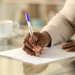 hand of black man writing on paper with a pen